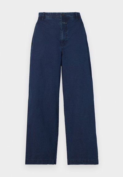 Bredde ben, mørk marineblå denimbukser med høy midje, som har knappelukking foran og sidelommer. Myk tekstur med minimal detaljering.