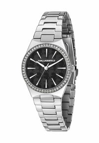 Silverfärgad klocka i metall med svart urtavla som har ett kamouflagemönster, kristalldetaljer runt boetten och ett länkarmband.