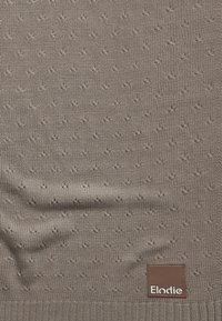 Kudottu ruskea villapaita, jossa on teksturoidut pisteet, ribbikangas kaulus ja ruskea nahkabrändilogo oikeassa alakulmassa.