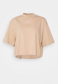 Beige zkrácený tričko s krátkým rukávem a stojá čkem, s malým bílým logem Nike umístěným přesně pod výstřihem.