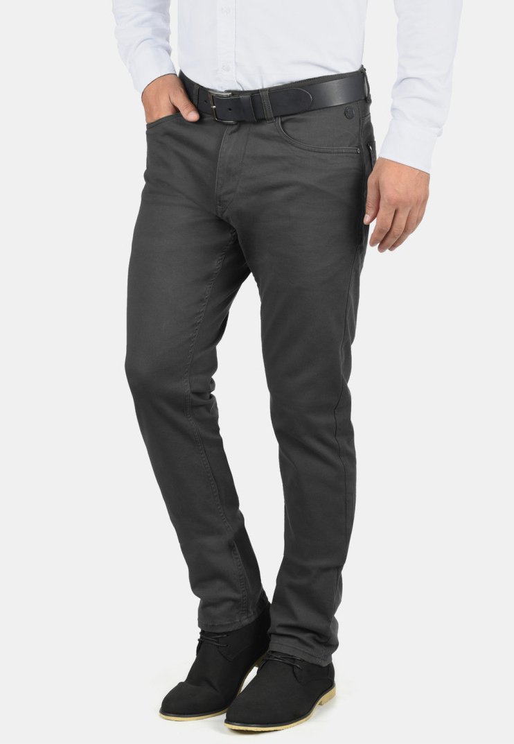 Mørkegrå jeans laget av denim, slim fit design, med sidelommer og knappelukking, sammen med svarte ankelstøvler og en hvit skjorte.
