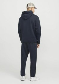 Sweatshirt à capuche bleu marine avec une texture lisse, associé à un jogging assorti. Comprend une poche kangourou et des coutures d'accent noir.