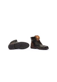 Botas de tobillo de cuero marrón y verde con superficie texturizada, punta redondeada y suela de goma. Presentan cordones, cremallera lateral y costura clásica.
