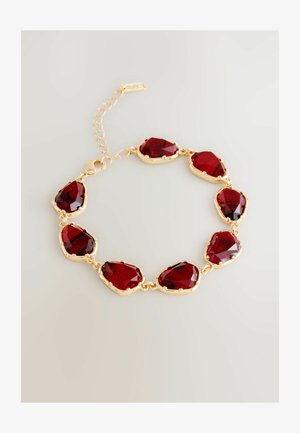 Arany lánc karkötő nyolc szabálytalan formájú, mélyvörös, fazettált kővel, állítható kapcsos lánccal, világos háttérrel.