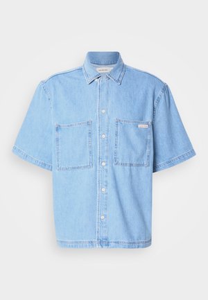 Chemise en denim bleu clair à manches courtes, avec un devant à boutons, deux poches poitrine et un col classique. Détails de couture remarquables.