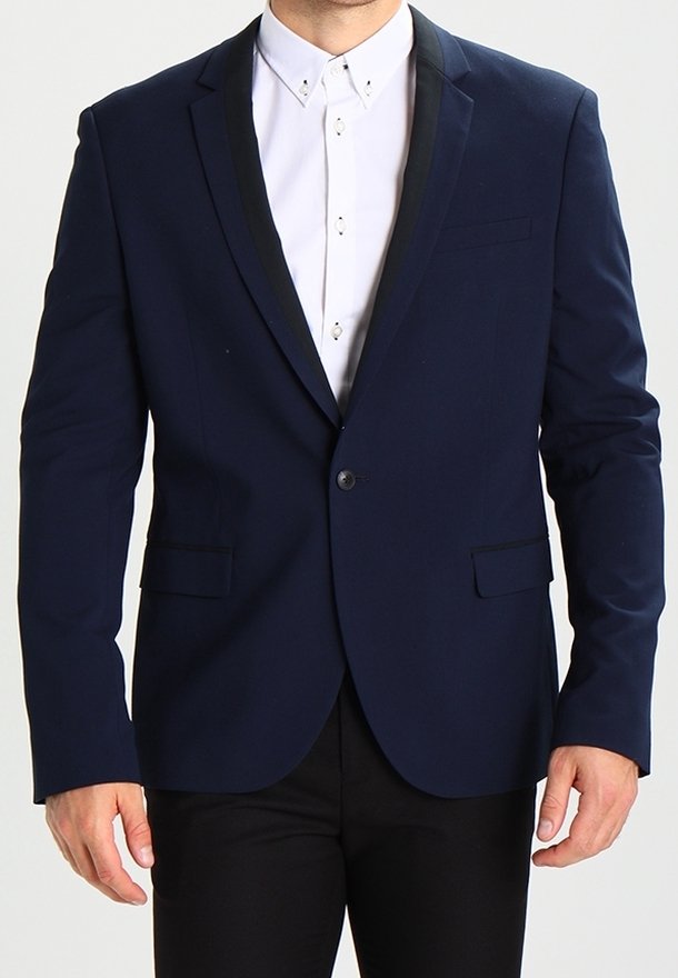 Marinblå kostymjacka med en elegant design, svart satinrevers, två framfickor, enkel knappstängning, matchad med en vit skjorta.