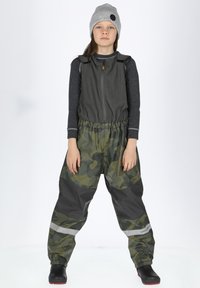 Vandtætte camouflage-overaller med grå fleecevest, elastisk talje, reflekterende detaljer, parret med en grå hue og sorte støvler.