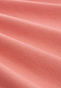 Rosa texturerad tyg med en ribbad yta, som visar mjuka veck och jämn färg genom hela ytan. Lämplig för olika textiltillämpningar.