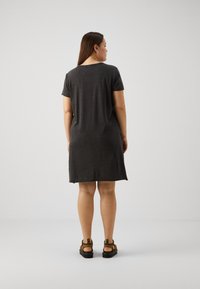 Pelēks īsām piedurknēm kleita ar brīvu piegriezumu, sasniedzot vidus augšstilbu, un gludu tekstūru. Apvienota ar izturīgām, ikdienas čībām.