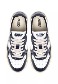 Sneakers in pelle bianca con dettagli blu navy, area delle dita traforata, lacci color crema e linguetta con logo. Presentano una suola spessa in gomma beige.