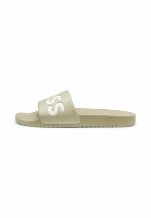 Beige Slide-Sandale mit breitem Riemen, auf dem erhöhte weiße „BOSS“-Buchstaben und eine strukturierte Sohle zu sehen sind.