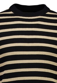 Czarny i beżowy prążkowany dzianinowy materiał z poziomymi paskami, widoczny na zbliżeniu górnej części swetra i obszaru przy szyi.