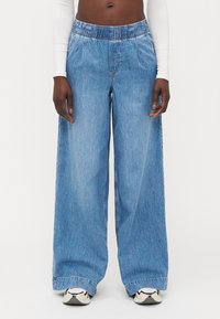 Svetlo modri široki jeans hlače z elastičnim pasom. Imajo sproščen kroj, ravno obliko in minimalne šive.