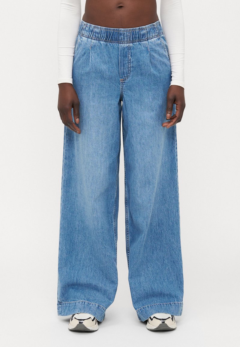 Svetlo modri široki jeans hlače z elastičnim pasom. Imajo sproščen kroj, ravno obliko in minimalne šive.