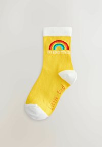 Calzino giallo brillante con una fascia bianca. Presenta un design arcobaleno e il testo "DIENSTAG" sopra l'arcobaleno e "Little Bird" sotto. Texture morbida.