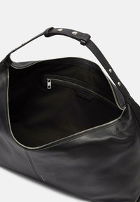 Czarna skórzana torba o teksturowanym wykończeniu, z suwakiem, pojedynczym paskiem i kieszenią wewnętrzną. Wnętrze wyłożone ciemnym materiałem.