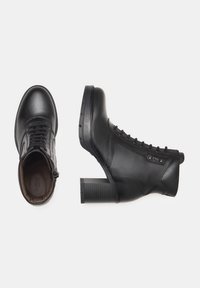 Zwarte leren enkelboots met een ronde neus, vetersluiting aan de voorkant en een gestructureerde blokhak. Gladde afwerking met minimale accenten aan de zijkanten.