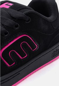 Μαύρο αθλητικό παπούτσι από σουέτ με ροζ λεπτομέρειες, μαύρα κορδόνια, και έντονο στυλιζαρισμένο λογότυπο "E" στο πλάι καθώς και το σήμα "etnies" στη σόλα.