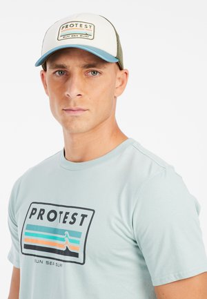 Lichtblauw katoenen t-shirt met 'PROTEST' logo en golfontwerp; witte mesh pet met groene accenten en logo patch aan de voorkant.