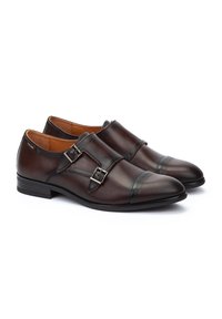 Bruine lederen schoenen met een gladde afwerking, voorzien van dubbele bevestigingen en een ronde neus. De zool is elegant en lichtjes gestructureerd.