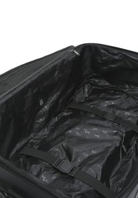Black suitcase interior with a smooth, shiny texture, featuring adjustable straps and a subtle logo pattern on the lining. Zippered closure.