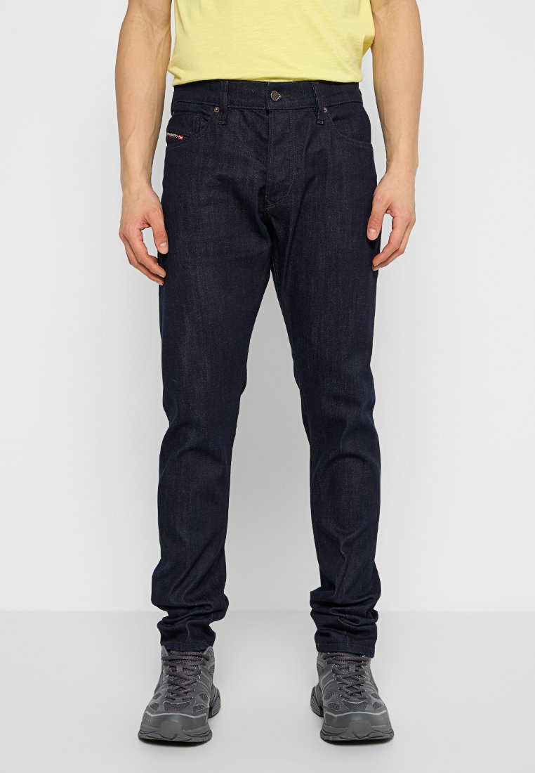 Jeans in denim blu scuro con vestibilità slim, dotati di chiusura a bottoni, cinque tasche e una piccola etichetta con logo sul davanti.