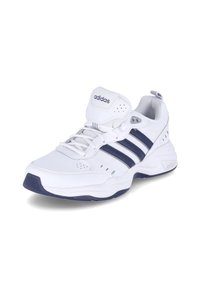 Chaussure de sport blanche avec des bandes bleu marine, des accents en mesh, un col rembourré autour de la cheville, et une semelle en caoutchouc texturée. Présente le logo de la marque sur le côté.