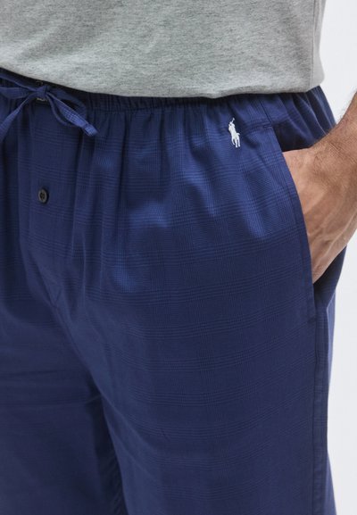 Granatowe szorty piżamowe w kratę wykonane z teksturowanej tkaniny, z elastycznym pasem, sznurkiem do regulacji i małym wyszywanym logo po lewej stronie.