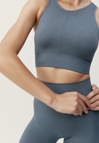 Grå sport-bh och högmidjade leggings tillverkade av texturerad tyg, med sömdetaljer och en åtsittande passform.