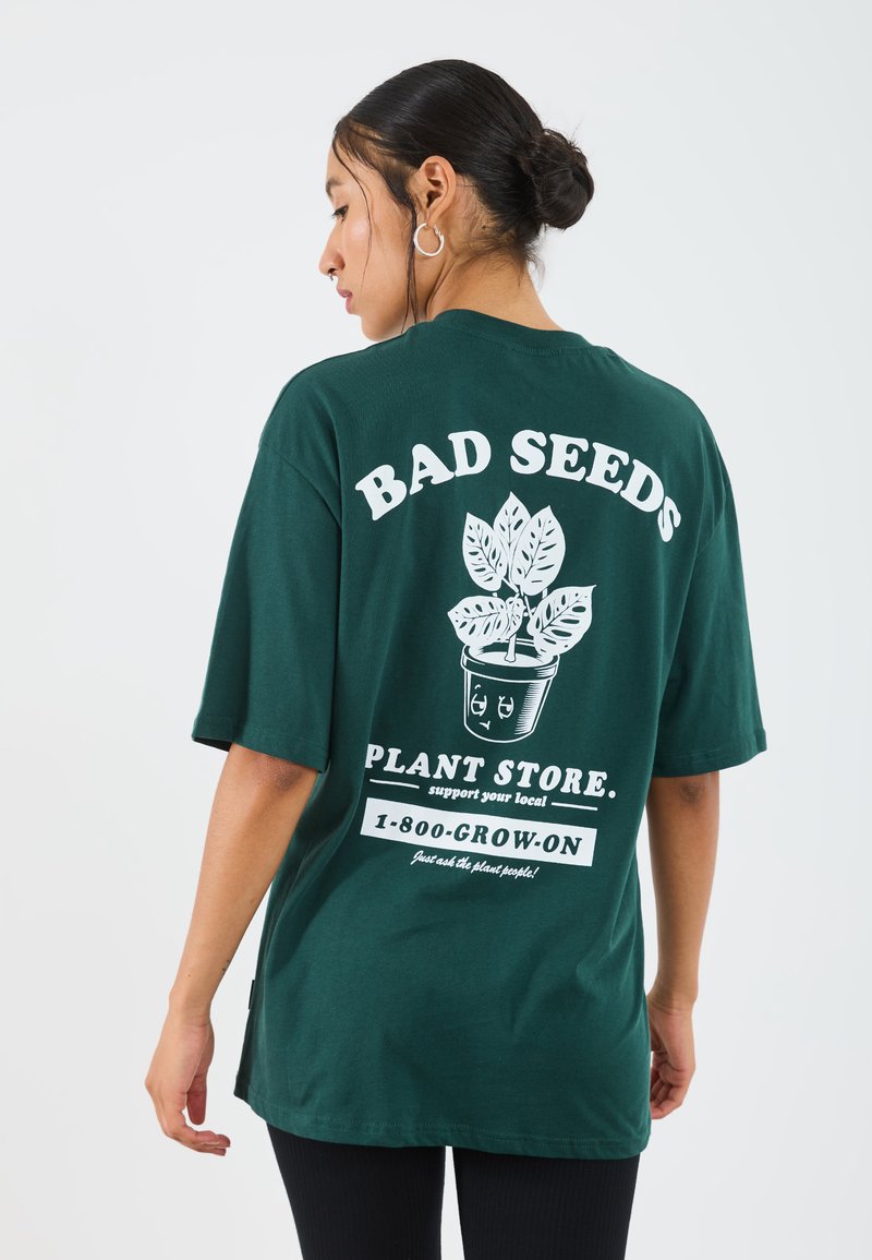 Dark green cotton t-shirt featuring white text and a plant graphic on the back. Short sleeves, relaxed fit, and a crew neckline.