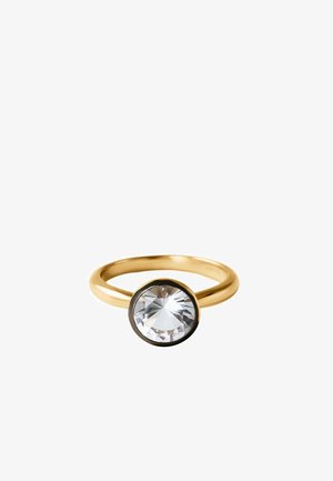 Anillo de oro con una piedra preciosa facetada redonda y clara, montada en un engaste biselado sobre un fondo blanco.