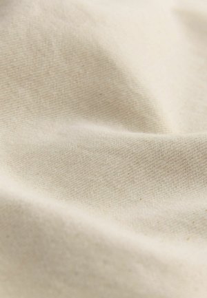 Bēšas kokvilnas audums ar mīkstu, gludu tekstūru, kuram ir smalka aušanas raksts; sakārtots, lai parādītu maigas krokas un rievas.