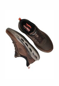 Zapatillas marrones con un upper de cuero suave y detalles de malla. Presenta una suela acolchada, diseño de cordones y una pestaña de tirador naranja.