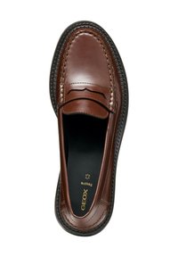 Mocasines de cuero marrón con diseño mocasín, que cuentan con costuras decorativas y una suela de goma negra. El interior es negro con un logotipo dorado.