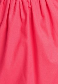 Tissu long et froncé en rose vif, présentant une texture lisse et une retombée uniforme. Les coutures sont serrées et régulières, sans motifs visibles.