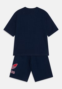 Tricou din bumbac bleu închis, cu mâneci scurte și guler rotund, asortat cu pantaloni scurți bleu închis care au un logo brodat roșu.