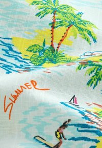 Färgglad tyg som visar en strandscen med palmer, vågor och en surfare. Har livfulla gröna, blå, gula och orangea toner.