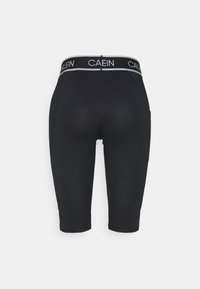 Shorts noirs moulants longueur genou avec une ceinture de marque affichant le texte "CA EIN KLEIN" sur fond blanc.