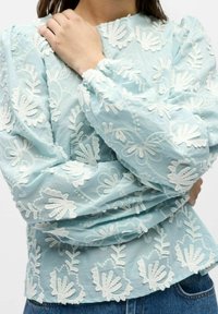 Lichtblauwe blouse met witte bloemrijke borduursels, pofmouwen, elastische manchetten en een licht geplooide zoomlijn. Gestructureerde stof.