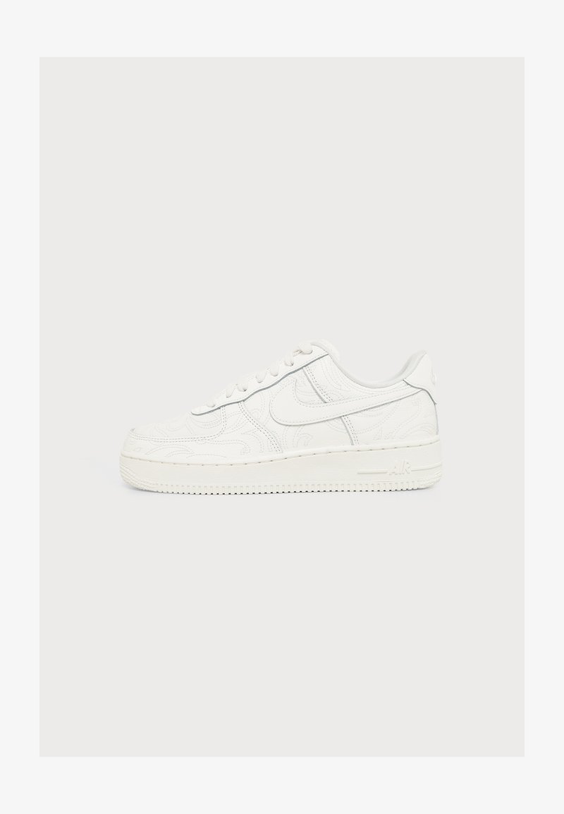 Λευκό αθλητικό παπούτσι Nike Air Force 1 με ανάγλυφα σπειροειδή σχέδια και λογότυπο Swoosh στο πλάι, πάνω σε απλό ανοιχτό φόντο.