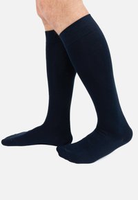 Calze navy fino al ginocchio realizzate in un materiale liscio e elastico, con un bordo a coste nella parte superiore e di colore uniforme.