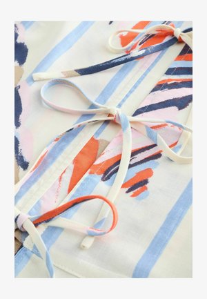 Tela multicolor con un patrón pictórico de franjas en naranja, azul y crema, acentuada con lazos de tela atados como cierres.