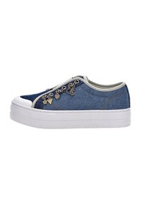 Matala denim tennarit valkoisella platolla, beige reunus ja koristeelliset metalliset riipukset sivuletsissä.