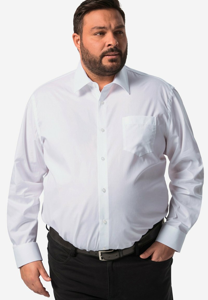 Biała, długosyowa koszula zapinana na guziki z kieszonką na piersi, z klasycznym kołnierzykiem i mankietami. Noszona z czarnymi spodniami i paskiem. Gładka tekstura.