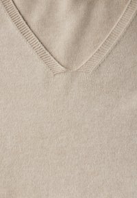 Beige Strickpullover mit einem V-Ausschnitt und gerippten Kanten sowie einer weichen Textur. Der Stoff hat eine dezente, gleichmäßige Webstruktur.