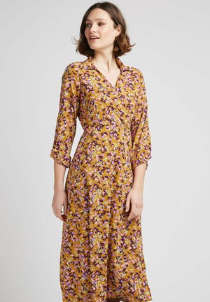Robe florale avec un fond moutarde, ornée de fleurs violettes, roses et vertes. Manches longues et décolleté en v, longueur genou. Fini satin.
