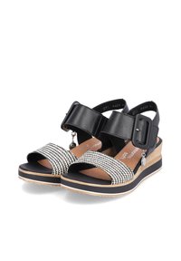 Sandales en cuir noir et tissu à motifs avec une large boucle. Elles présentent un talon compensé et un design à bout ouvert, avec une semelle texturée pour une meilleure adhérence.