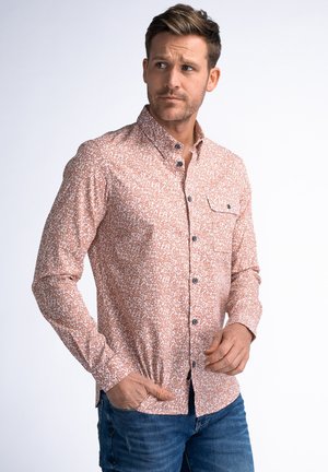 Camisa de botones de manga larga en rosa claro con patrón abstracto blanco, que incluye un bolsillo en el pecho, botones negros y un diseño ajustado.