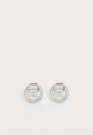 Orecchini in metallo argentato con una pietra rettangolare sopra un cerchio. Texture liscia, design minimalista e forma geometrica.