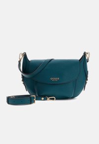 Torba crossbody z miękkiej skóry w kolorze morskim z fakturowanym wykończeniem, złotymi okuciami i regulowanym paskiem. Posiada zapięcie na klapę i tłoczone logo.